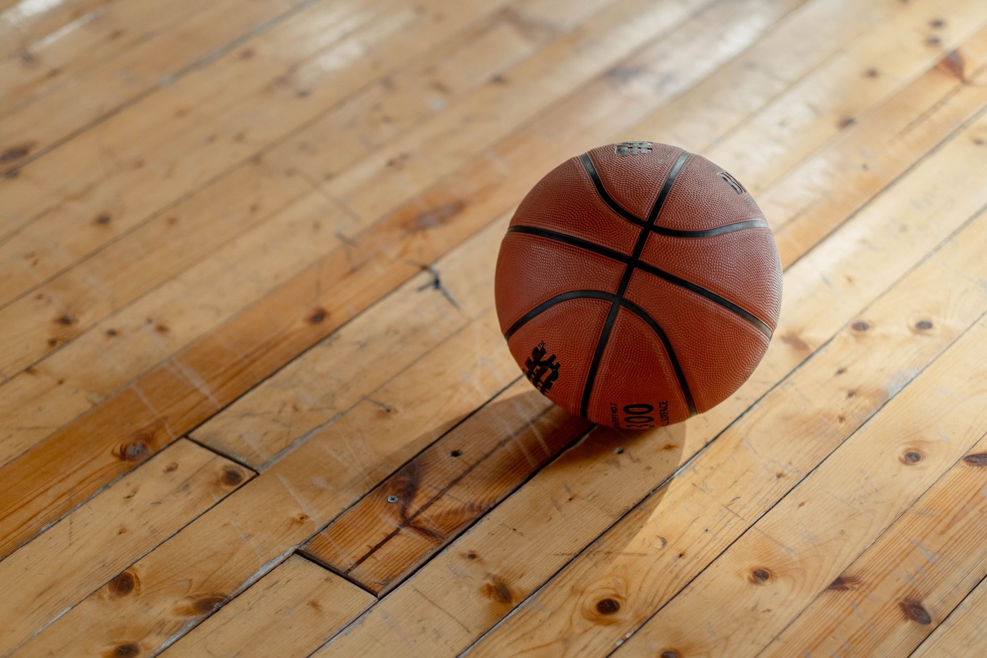 Basketball resting on a wooden gym floor